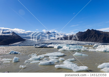 Floating icebergs on Fjallsarlon lagoon beneath Fjallsjokull glacier, Iceland Floating icebergs on Fjallsarlon lagoon beneath Fjallsjokull glacier, Iceland 143123350