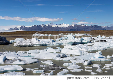 Icebergs floating on Fjallsarlon lagoon beneath snowy mountains in Iceland Icebergs floating on Fjallsarlon lagoon beneath snowy mountains in Iceland 143123361