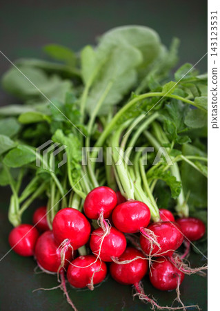 Close-up of fresh red radishes with green leaves, organic vegetable harvest concept Close-up of fresh red radishes with green leaves, organic vegetable harvest concept 143123531