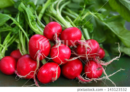 Close-up of fresh red radishes with green leaves, organic vegetable harvest concept Close-up of fresh red radishes with green leaves, organic vegetable harvest concept 143123532
