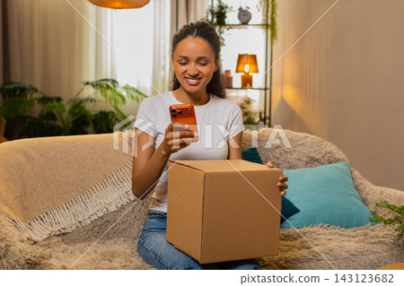 African American young woman on home sofa pleased after refund approval for defective delivery box African American young woman on home sofa pleased after refund approval for defective delivery box 143123682