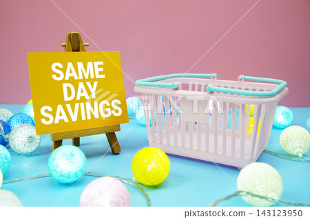 Same Day Savings text with shopping basket on blue background Same Day Savings text with shopping basket on blue background 143123950