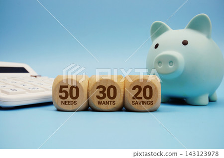 50-30-20 Savings Rule alphabet letters with calculator and piggy bank on blue background 50-30-20 Savings Rule alphabet letters with calculator and piggy bank on blue background 143123978