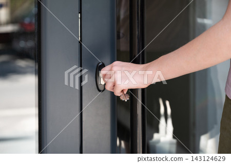 Person Opening Front Door of Modern Home in Daylight Person Opening Front Door of Modern Home in Daylight 143124629