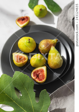 Fresh Ripe Figs with Green Leaves on Dark Ceramic Plate Fresh Ripe Figs with Green Leaves on Dark Ceramic Plate 143124635