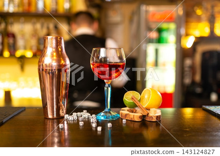 Alcoholic cocktail, shaker and dice on bar counter Alcoholic cocktail, shaker and dice on bar counter 143124827
