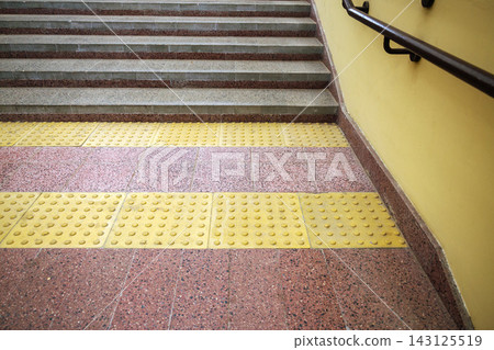 Yellow tactile paving tiles in front of concrete staircase steps creating barrier free environment in public area Yellow tactile paving tiles in front of concrete staircase steps creating barrier free environment in public area 143125519