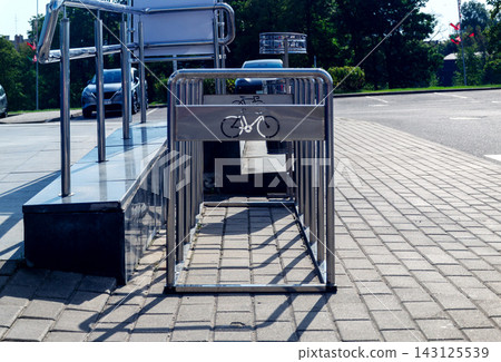 Empty metal bicycle rack standing on paved sidewalk near street parking zone outdoors for urban transport infrastructure Empty metal bicycle rack standing on paved sidewalk near street parking zone outdoors for urban transport infrastructure 143125539