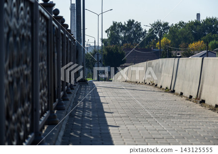 Empty bridge walkway with concrete block barrier and metal railing under blue sky with copy space for urban construction concepts Empty bridge walkway with concrete block barrier and metal railing under blue sky with copy space for urban construction concepts 143125555