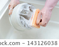 A housewife's hands washing dishes in the kitchen sink 143126038