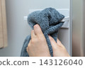 A housewife wipes her hands on the towel rack in the refrigerator. 143126040