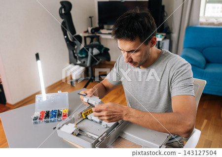 Concentrated technician or engineer working on switchboard installation. Hands on with tools and components, showing skill and precision in a modern workspace. DIY project or professional job. 143127504