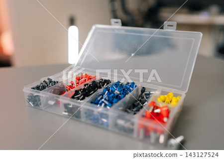 Closeup of various insulated crimp connectors for wiring work. Set of tools for electrician or DIY projects. Shallow depth of field with soft light in workshop background. Closeup of various insulated crimp connectors for wiring work. Set of tools for electrician or DIY projects. Shallow depth of field with soft light in workshop background. 143127524