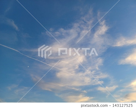 夕陽西下,天空中出現一彎新月和飛機尾跡。 夕陽西下,天空中出現一彎新月和飛機尾跡。 143127525
