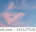 Clouds and a crescent moon bathed in the setting sun 143127528