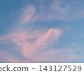 Clouds and a crescent moon bathed in the setting sun 143127529