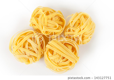 Four nests of raw tagliatelle pasta isolated on a white background. Four nests of raw tagliatelle pasta isolated on a white background. 143127751