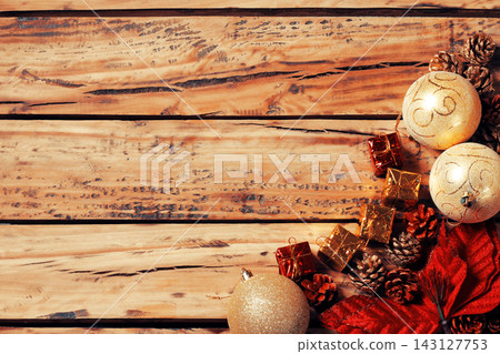 Christmas background with a frame, gold ornaments, gifts, and pine cones on weathered wood, with space for text. Christmas background with a frame, gold ornaments, gifts, and pine cones on weathered wood, with space for text. 143127753