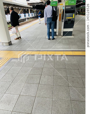 在日本火車站的月台上,人們正在使用綠色汽車票自動售票機購票。 在日本火車站的月台上,人們正在使用綠色汽車票自動售票機購票。 143128526