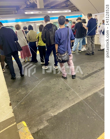 人們在擁擠的火車站月台上等候火車。 143128528