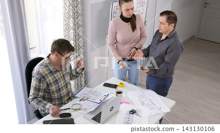 The company's manager and accountant are standing at the chief architect's desk and talking about a new project. Approval of the budget The company's manager and accountant are standing at the chief architect's desk and talking about a new project. Approval of the budget 143130106