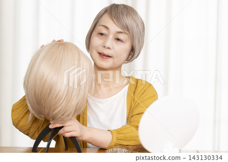 有些老年婦女因為擔心頭髮稀疏而戴假髮。 有些老年婦女因為擔心頭髮稀疏而戴假髮。 143130334