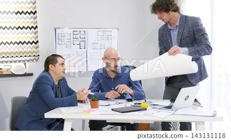 Three men are discussing blueprints and construction plans. A young employee of the architectural bureau coordinates his project with his superiors Three men are discussing blueprints and construction plans. A young employee of the architectural bureau coordinates his project with his superiors 143131118