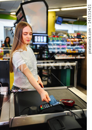 Customer paying with credit card at supermarket checkout Customer paying with credit card at supermarket checkout 143131421