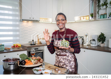 Smiling woman holding Brussels sprouts preparing healthy meal in modern kitchen Smiling woman holding Brussels sprouts preparing healthy meal in modern kitchen 143131452