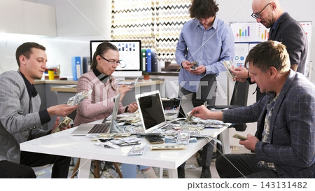 Gamblers count the money won in online casinos. A group of people are sitting at a table with money and laptops Gamblers count the money won in online casinos. A group of people are sitting at a table with money and laptops 143131482