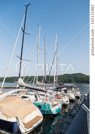 Boats moored beside a marina pier on a calm summer day Boats moored beside a marina pier on a calm summer day 143131862