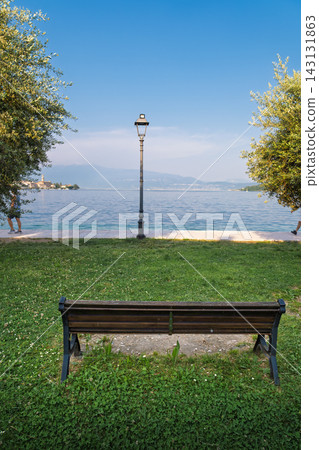Empty bench overlooking a peaceful lake on a sunny day Empty bench overlooking a peaceful lake on a sunny day 143131863