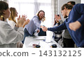 The company's employees celebrate a successful transaction. A group of people shake hands and applaud. The scene is positive and friendly 143132125