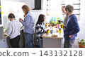 A group of young entrepreneurs organized a coffee break in the office kitchen of the family office. The staff is gathered around the kitchen table 143132128