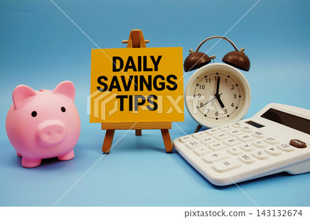 Daily Savings Tips text with piggy bank, alarm clock and calculator on blue background Daily Savings Tips text with piggy bank, alarm clock and calculator on blue background 143132674