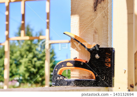 Staple gun resting on wooden beam inside unfinished timber frame. Staple gun resting on wooden beam inside unfinished timber frame. 143132694