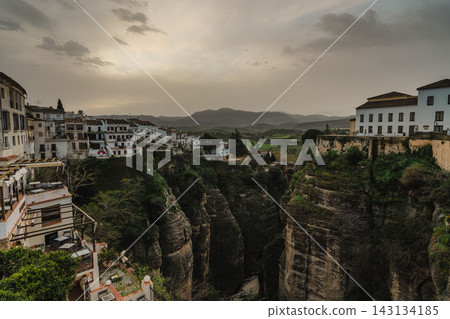 Green Tajo gorge and valley with whitewashed houses and hazy mountains in Ronda, Spain Green Tajo gorge and valley with whitewashed houses and hazy mountains in Ronda, Spain 143134185
