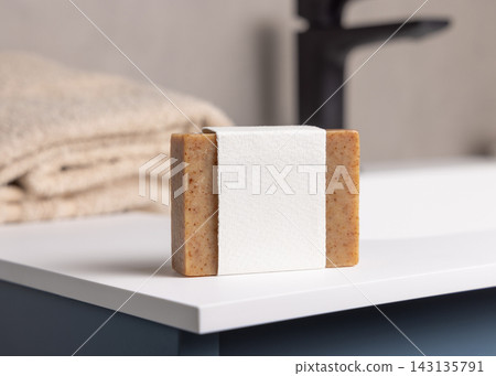 Brown soap bar with blank label mockup near beige towel in blue bathroom closeup Brown soap bar with blank label mockup near beige towel in blue bathroom closeup 143135791