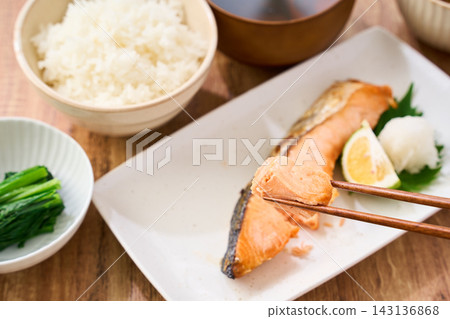 在家享用傳統的日式早餐,用筷子夾起烤鮭魚,配上白飯一起吃。 在家享用傳統的日式早餐,用筷子夾起烤鮭魚,配上白飯一起吃。 143136868