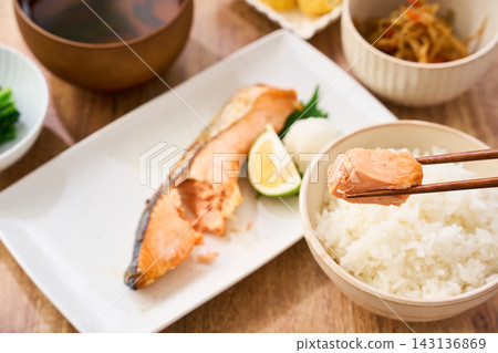 在家享用傳統的日式早餐,用筷子夾起烤鮭魚,配上白飯一起吃。 在家享用傳統的日式早餐,用筷子夾起烤鮭魚,配上白飯一起吃。 143136869