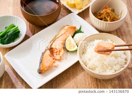 在家享用傳統的日式早餐,用筷子夾起烤鮭魚,配上白飯一起吃。 在家享用傳統的日式早餐,用筷子夾起烤鮭魚,配上白飯一起吃。 143136870