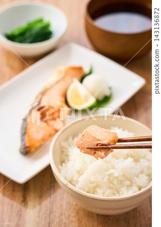 A traditional Japanese breakfast at home, where you pick up grilled salmon with chopsticks and enjoy it with white rice. A traditional Japanese breakfast at home, where you pick up grilled salmon with chopsticks and enjoy it with white rice. 143136872