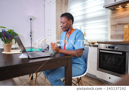African american nurse consulting online from home kitchen African american nurse consulting online from home kitchen 143137192