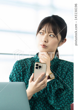 A woman/businesswoman thinking with a smartphone A woman/businesswoman thinking with a smartphone 143138196