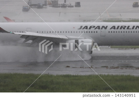 一架客機降落在下著雨的跑道上,引擎的反推力噴出一股水柱。 一架客機降落在下著雨的跑道上,引擎的反推力噴出一股水柱。 143140951