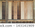 The vertical plank exterior wall of a wooden building that has changed over time. 143141909