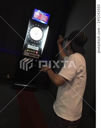 夜幕降臨,一名男子在室內休閒區投擲飛鏢,旁邊還有一台飛鏢機。 夜幕降臨,一名男子在室內休閒區投擲飛鏢,旁邊還有一台飛鏢機。 143142082