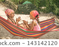 Children play with their hands while sitting in a hammock on the beach of the Campground. Camping on summer holidays 143142120