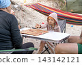 Family camping and outdoor board games. The girl rolls the dice on the game board. 143142121
