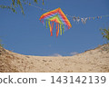 An airborne rainbow kite and a swimsuit are drying on a clothesline on the beach. Summer relaxation and entertainment. 143142139